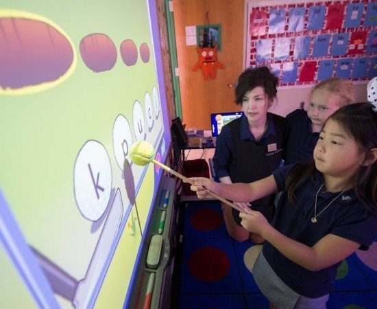 Teachers and students work together in front of a smart board